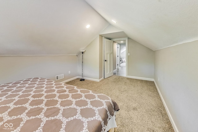 unfurnished bedroom with vaulted ceiling, light colored carpet, and a textured ceiling