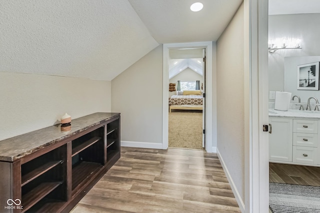 interior space with sink, light carpet, a textured ceiling, and vaulted ceiling