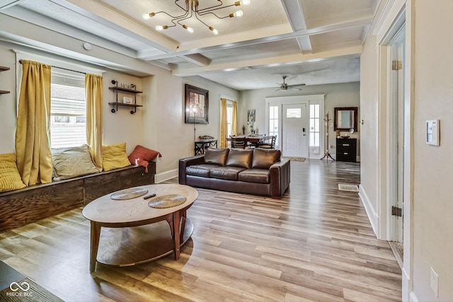 living room featuring ceiling fan with notable chandelier, a wealth of natural light, coffered ceiling, and light hardwood / wood-style flooring