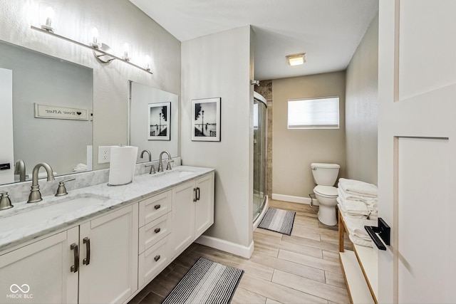 bathroom with toilet, double vanity, and a shower with door