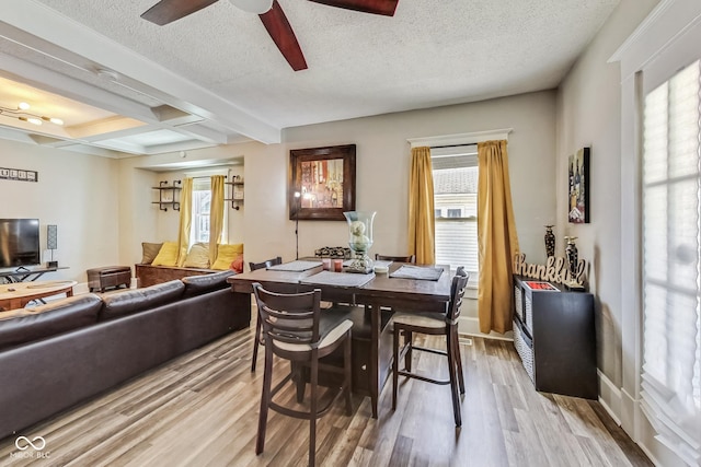 dining space with light wood-type flooring, a wealth of natural light, ceiling fan, and beamed ceiling