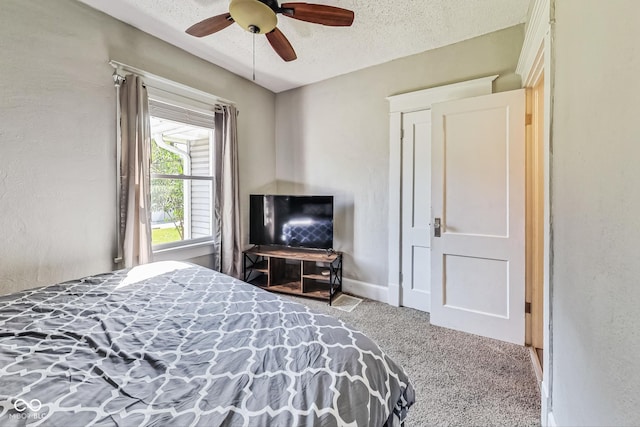 carpeted bedroom featuring ceiling fan and a textured ceiling