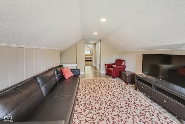 living room featuring a textured ceiling, light hardwood / wood-style floors, and lofted ceiling