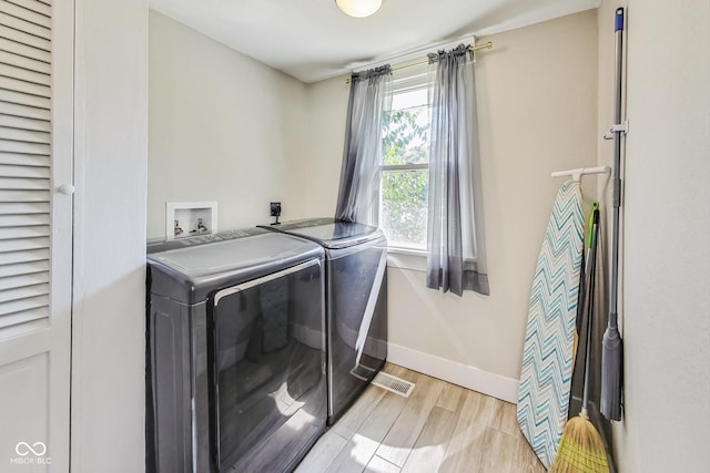 laundry area featuring light wood-type flooring and separate washer and dryer