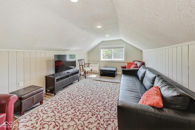 living room with hardwood / wood-style flooring, a textured ceiling, and lofted ceiling