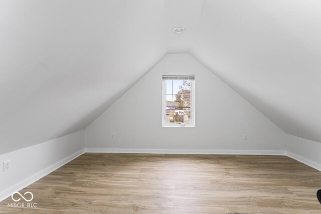 1046 Dawson St, Indianapolis, IN 46203 - additional living space with baseboards, vaulted ceiling, and light wood-style floors