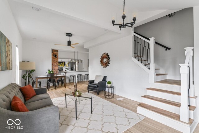 living room featuring ceiling fan with notable chandelier and wood-type flooring