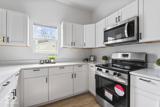 1046 Dawson St, Indianapolis, IN 46203 - kitchen featuring white cabinetry, light wood-style flooring, light countertops, and appliances with stainless steel finishes