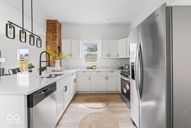 1046 Dawson St, Indianapolis, IN 46203 - kitchen with light countertops, a peninsula, appliances with stainless steel finishes, white cabinetry, and a sink