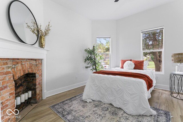 1046 Dawson St, Indianapolis, IN 46203 - bedroom featuring baseboards, wood finished floors, and a brick fireplace