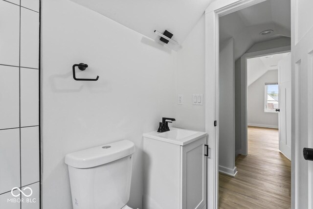 1046 Dawson St, Indianapolis, IN 46203 - half bath with vaulted ceiling, toilet, a sink, wood finished floors, and baseboards