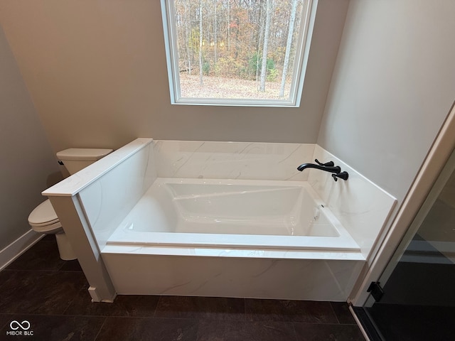 bathroom featuring tile patterned floors, toilet, and tiled tub