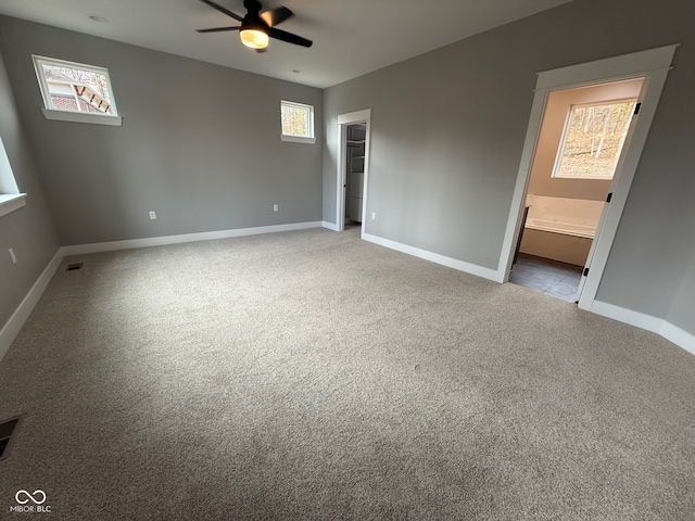 unfurnished bedroom with light carpet, ensuite bathroom, ceiling fan, a spacious closet, and a closet