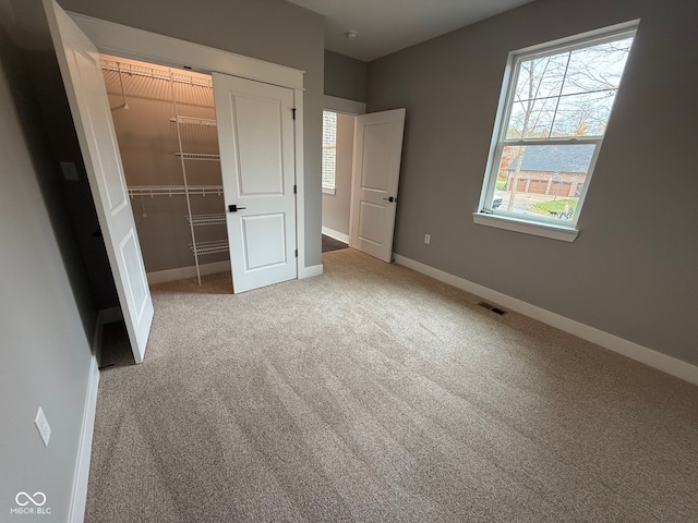 unfurnished bedroom with light carpet and a closet