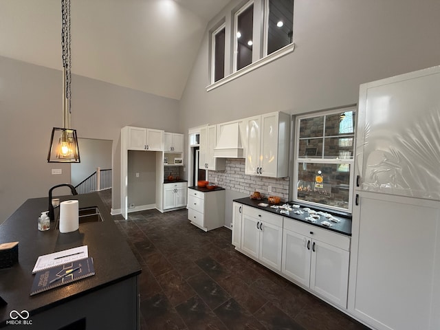 kitchen with sink, hanging light fixtures, high vaulted ceiling, dark hardwood / wood-style floors, and white cabinets