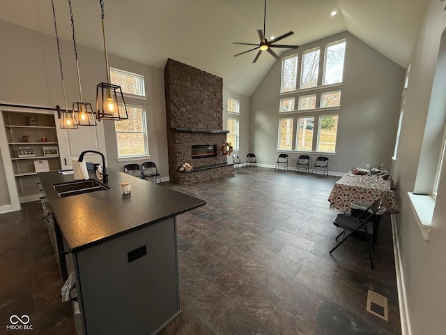 3380 N Pine Song Dr, Martinsville, IN 46151 - kitchen featuring a sink, dark countertops, ceiling fan, high vaulted ceiling, and a stone fireplace