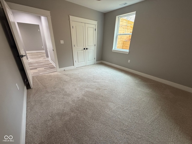 unfurnished bedroom featuring light carpet and a closet