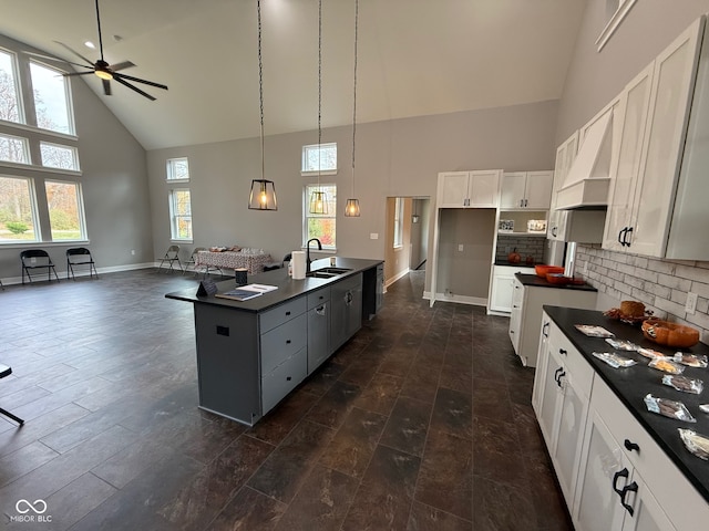 kitchen with white cabinetry, sink, high vaulted ceiling, an island with sink, and pendant lighting