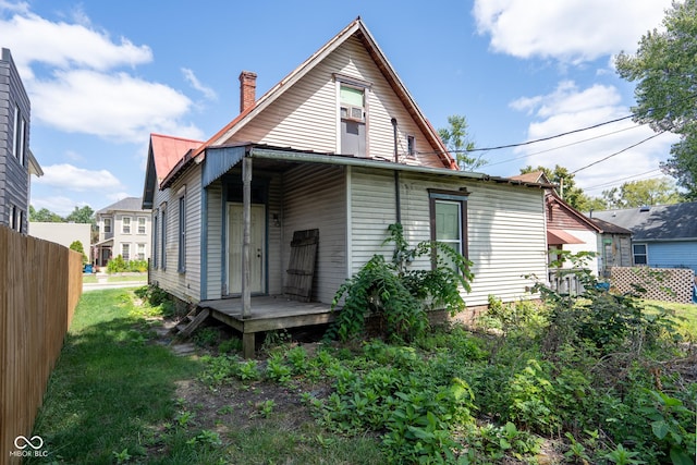 back of property featuring metal roof, a lawn, and fence