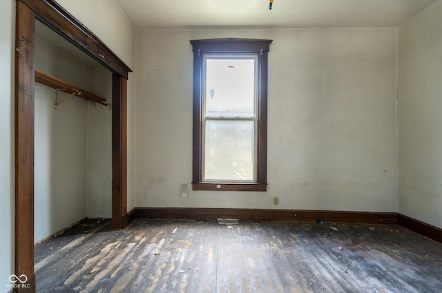 unfurnished bedroom featuring a closet, wood-type flooring, and baseboards