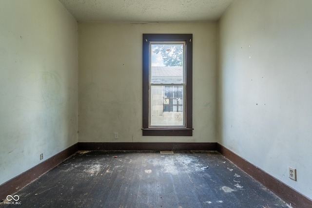 spare room with a textured ceiling and baseboards