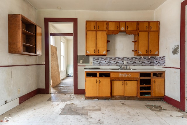 kitchen with open shelves, a sink, light countertops, and brown cabinets