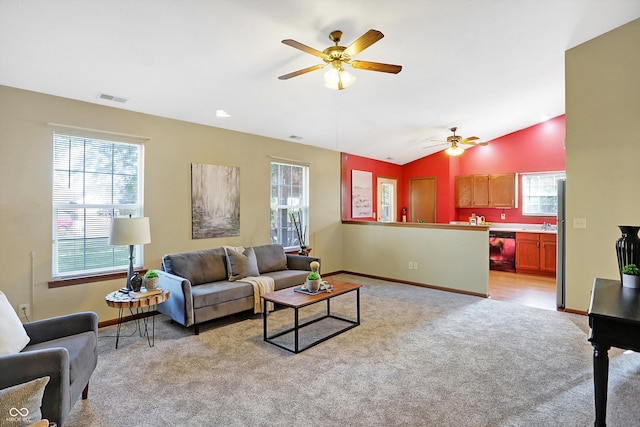 living room with a healthy amount of sunlight, ceiling fan, light carpet, and vaulted ceiling