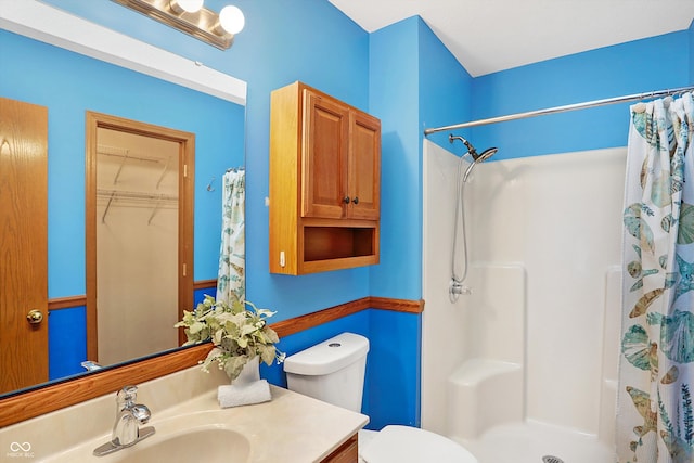 bathroom featuring a shower with shower curtain, toilet, and vanity