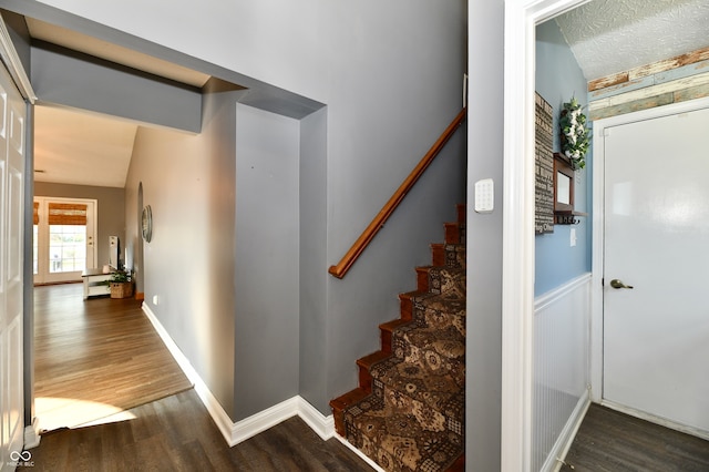 stairs featuring hardwood / wood-style floors, a textured ceiling, and vaulted ceiling