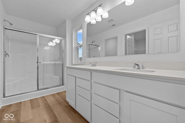 bathroom with wood-type flooring, vanity, and an enclosed shower