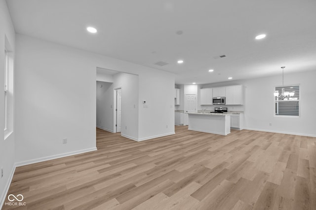 unfurnished living room featuring light hardwood / wood-style flooring and an inviting chandelier