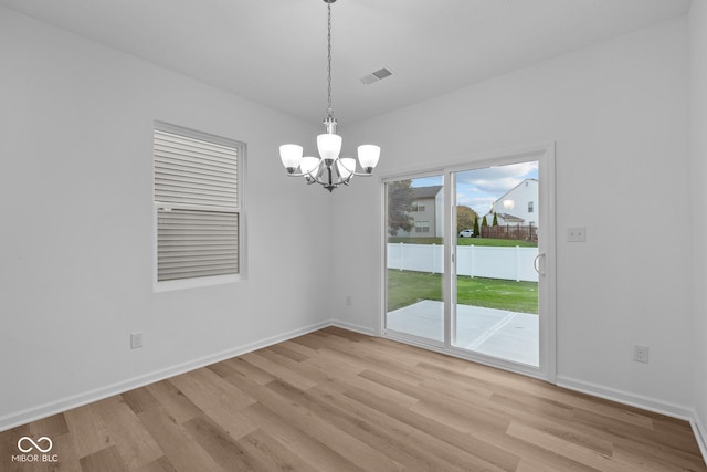 unfurnished dining area featuring light hardwood / wood-style flooring and a chandelier