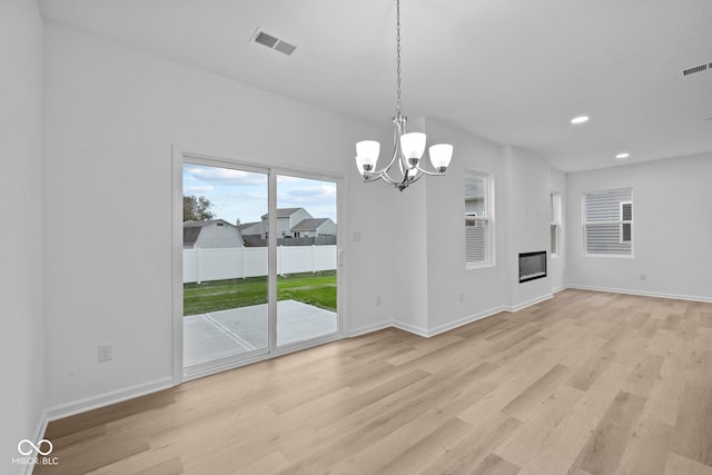 unfurnished dining area featuring an inviting chandelier and light wood-type flooring