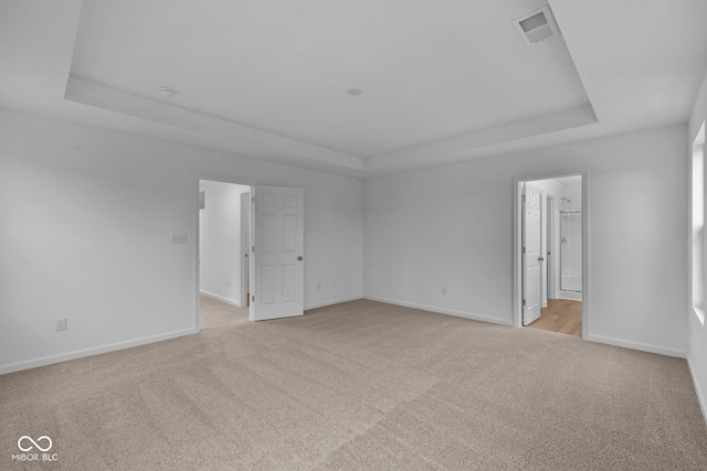 carpeted empty room with a tray ceiling