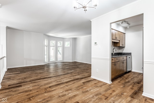 unfurnished living room with an inviting chandelier, baseboards, dark wood-style flooring, and a sink