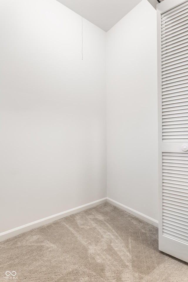 empty room featuring baseboards and light carpet