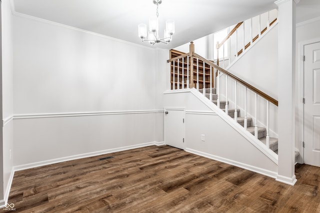 staircase with an inviting chandelier, crown molding, wood finished floors, and baseboards