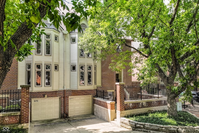 view of front of property with brick siding, concrete driveway, an attached garage, and fence