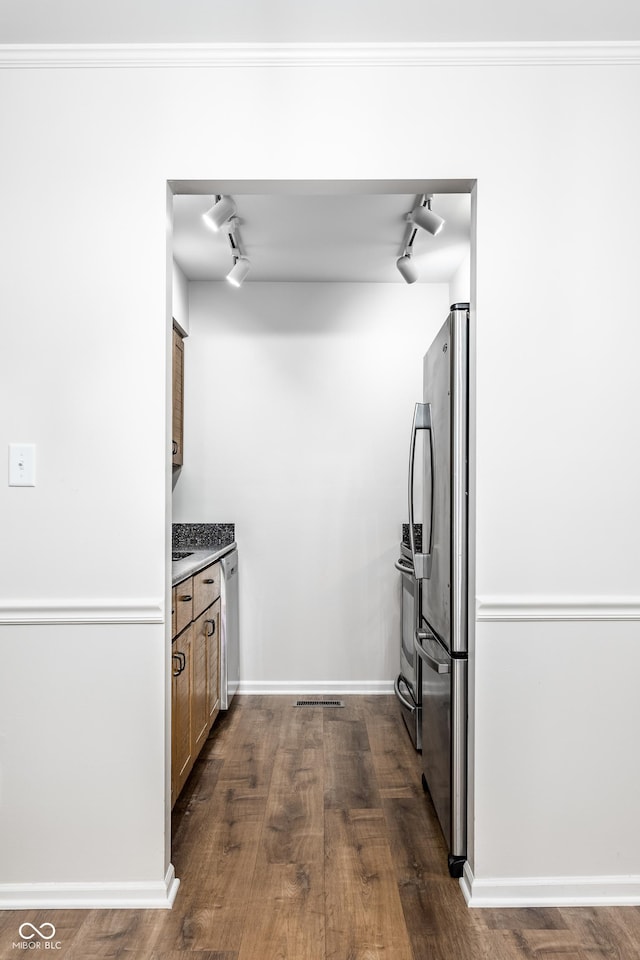 kitchen featuring stainless steel appliances, rail lighting, crown molding, baseboards, and dark wood-style flooring