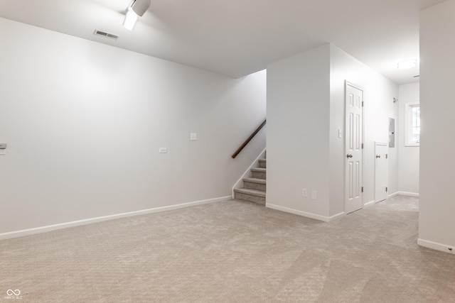 basement with visible vents, baseboards, stairs, light carpet, and electric panel