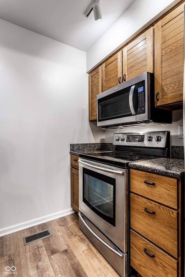 kitchen with brown cabinetry, baseboards, visible vents, appliances with stainless steel finishes, and light wood-type flooring