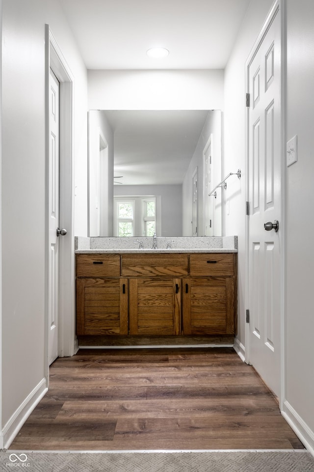 bathroom featuring baseboards, wood finished floors, and vanity