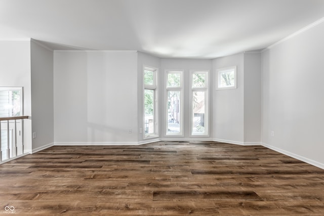 empty room with baseboards, dark wood-type flooring, and crown molding