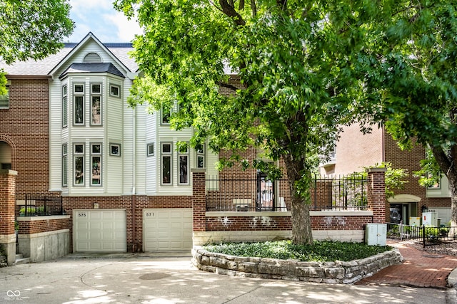 view of front of home featuring a garage, brick siding, driveway, and fence