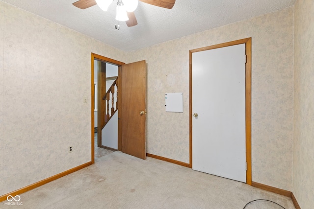 carpeted spare room featuring a textured ceiling and ceiling fan