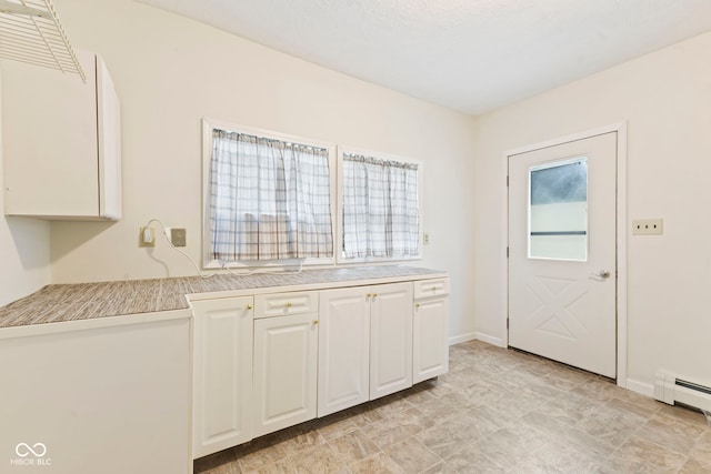 kitchen with a baseboard radiator and white cabinets