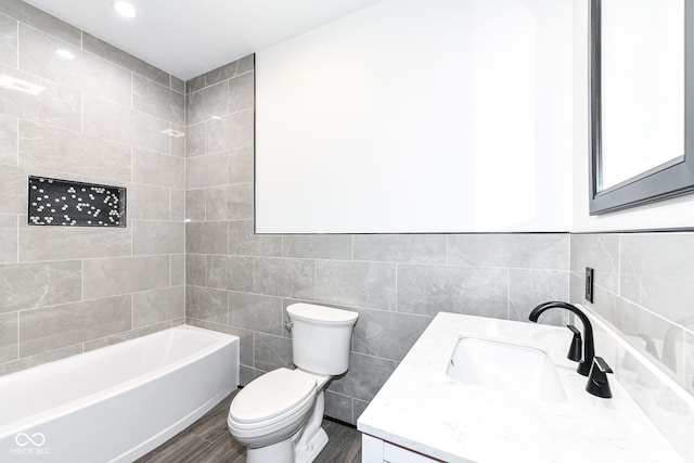 full bath featuring washtub / shower combination, toilet, vanity, wood finished floors, and tile walls