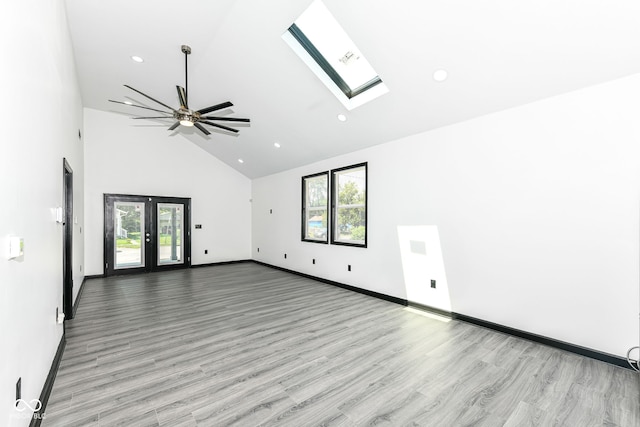 unfurnished room featuring baseboards, high vaulted ceiling, a skylight, recessed lighting, and light wood-style floors