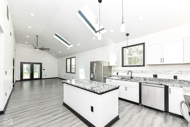 kitchen featuring a wealth of natural light, a center island, appliances with stainless steel finishes, and a sink