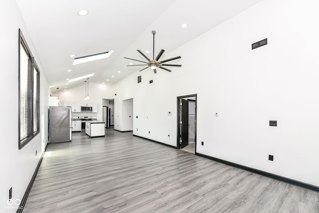 unfurnished living room featuring baseboards, high vaulted ceiling, a skylight, recessed lighting, and light wood-type flooring